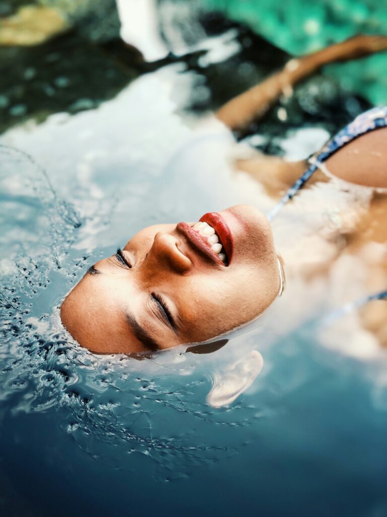 african-american woman floating in body of water looking peaceful and relaxed, hydrotherapy